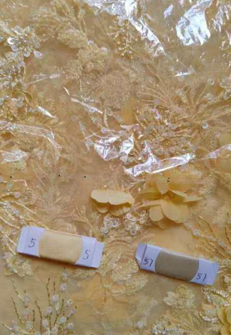 Yellow fabric with lace details and three labeled samples on a textured surface.