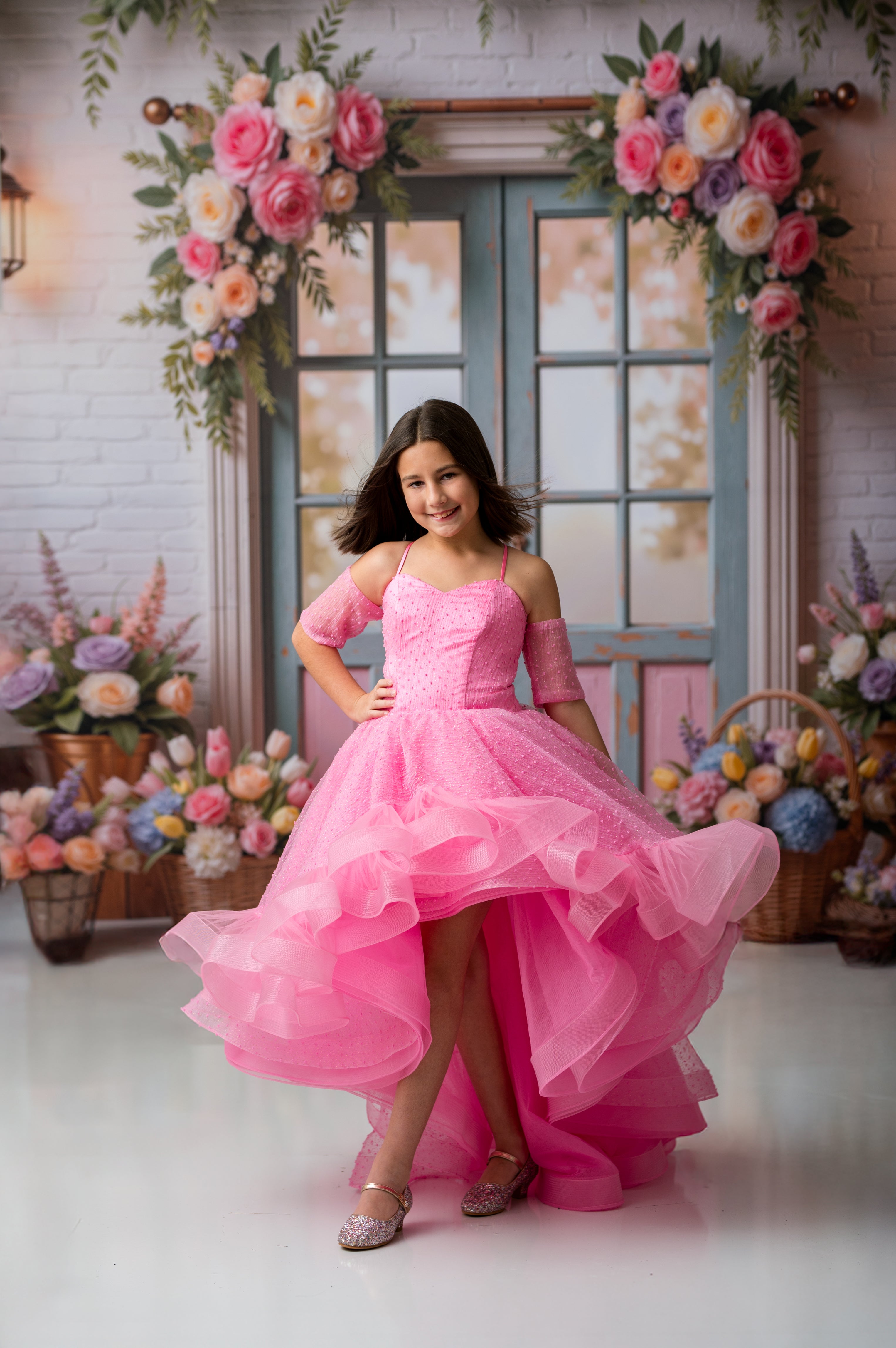 Woman in a pink dress standing in a decorated room with flowers.