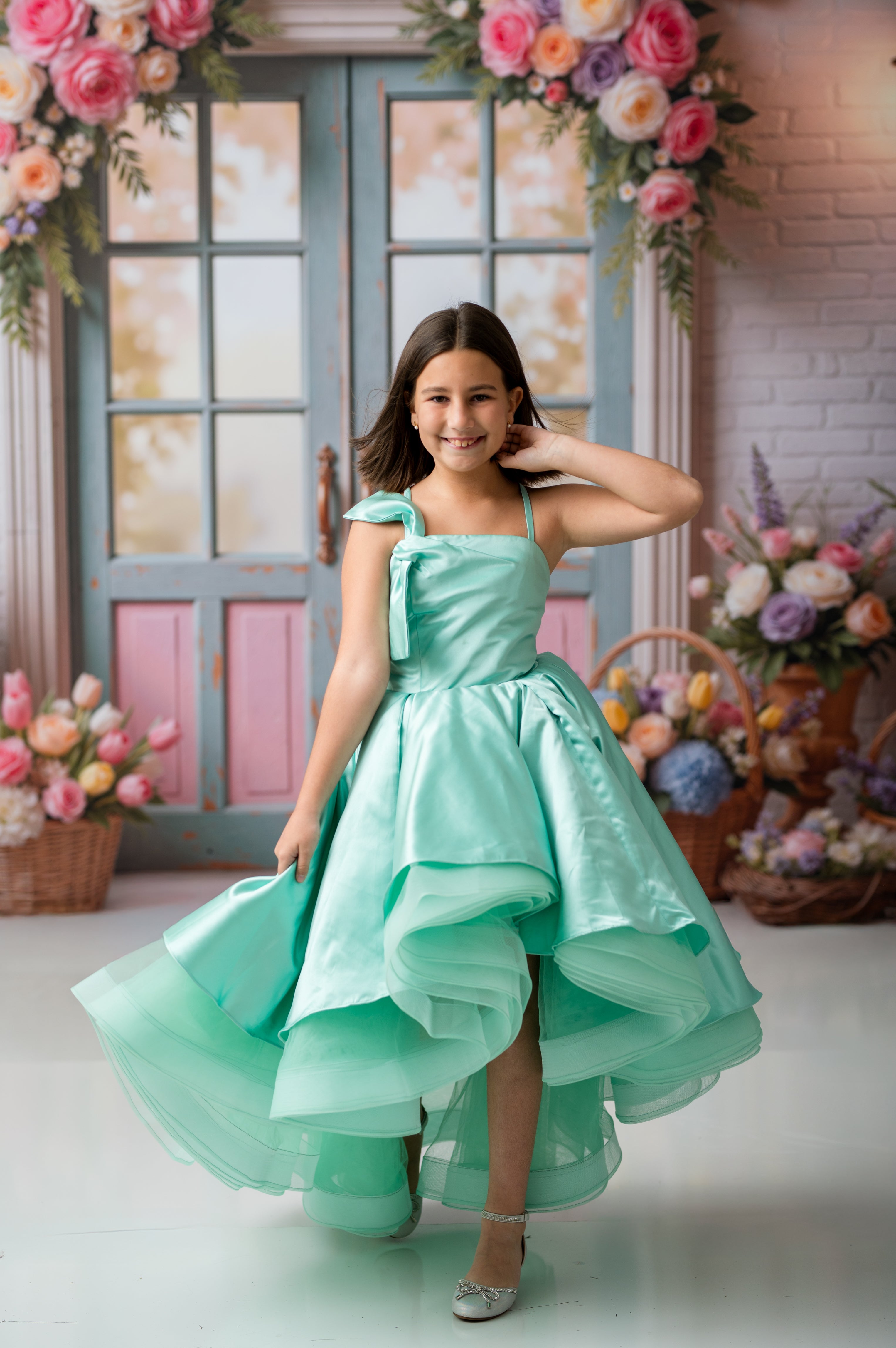 Woman in a light blue dress standing in a decorated room with flowers and baskets.