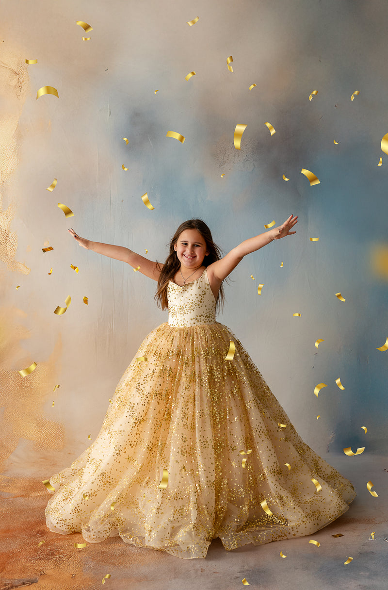 Girl twirling in gold star glitter gown with full tulle skirt


