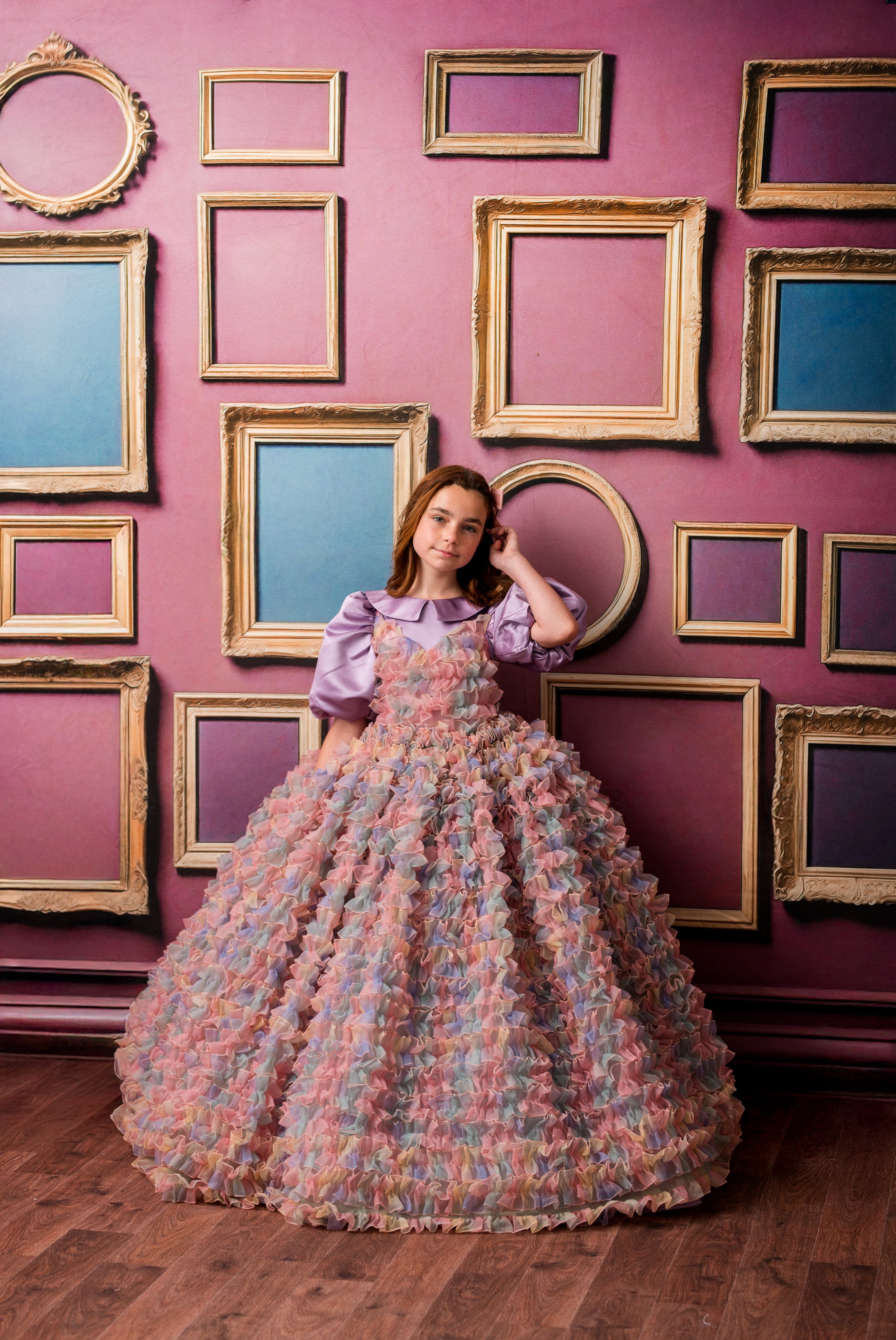 Woman in a floral dress standing in front of a wall with framed pictures.