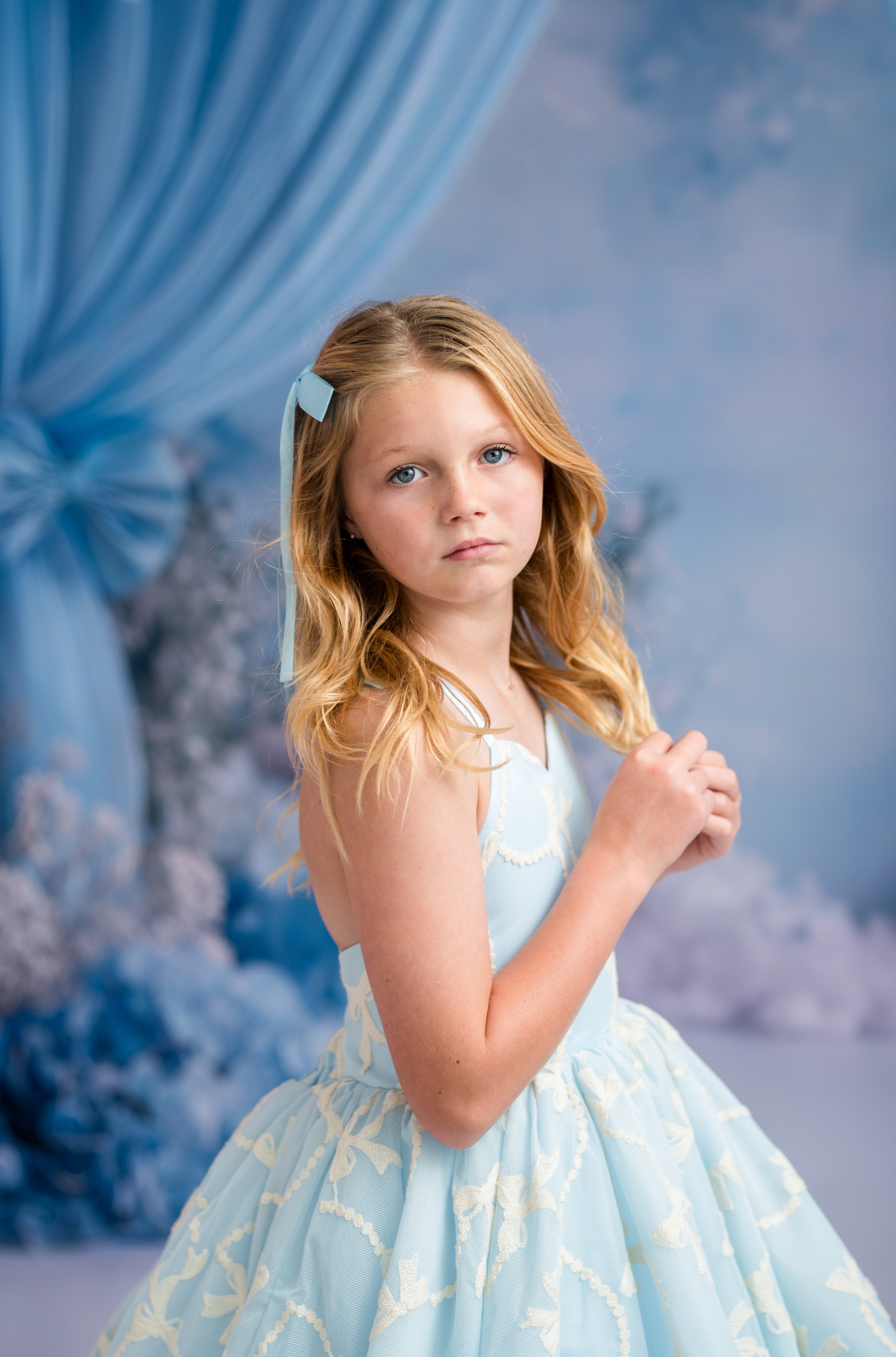 Young girl in a light blue dress with gold patterns against a snowy backdrop
