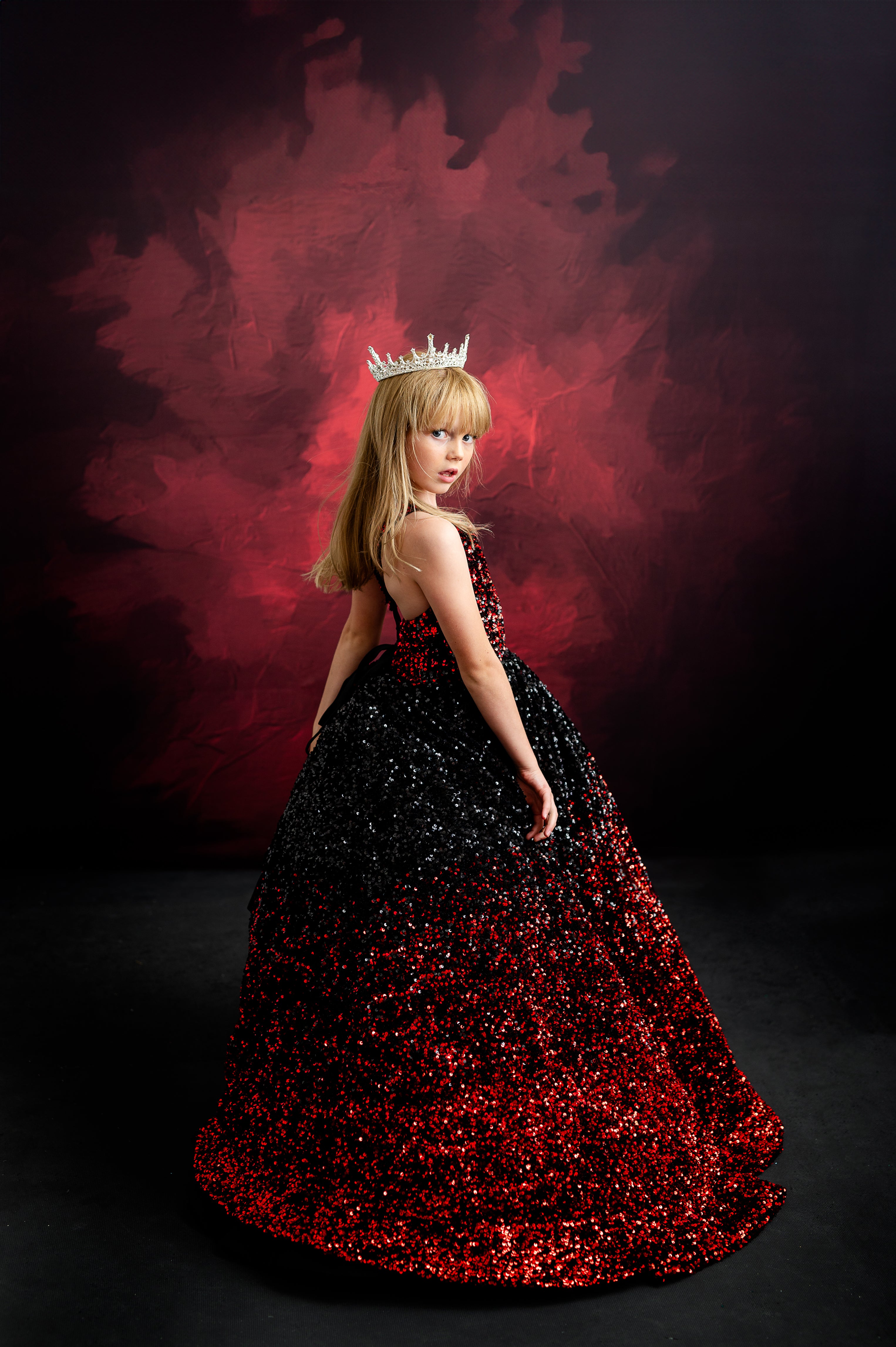 Young girl twirling in a dazzling gown, channeling Taylor Swift's signature blend of elegance and confidence with a royal crown.
