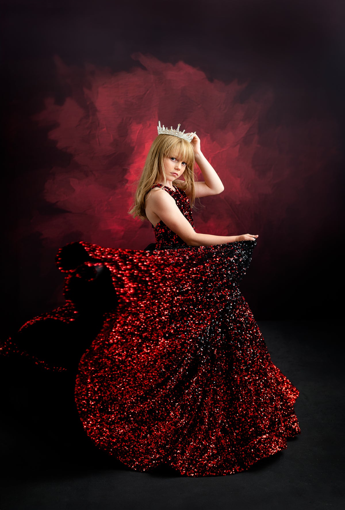 Model in a glittering black and red ball gown inspired by Taylor Swift’s bold and fearless style, set against a dark, moody background.
