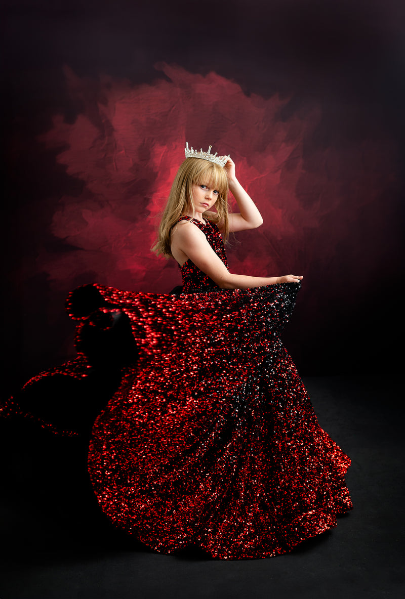 Model in a glittering black and red ball gown inspired by Taylor Swift’s bold and fearless style, set against a dark, moody background.
