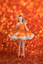 Young girl in an orange dress with a white skirt against a glittery orange background