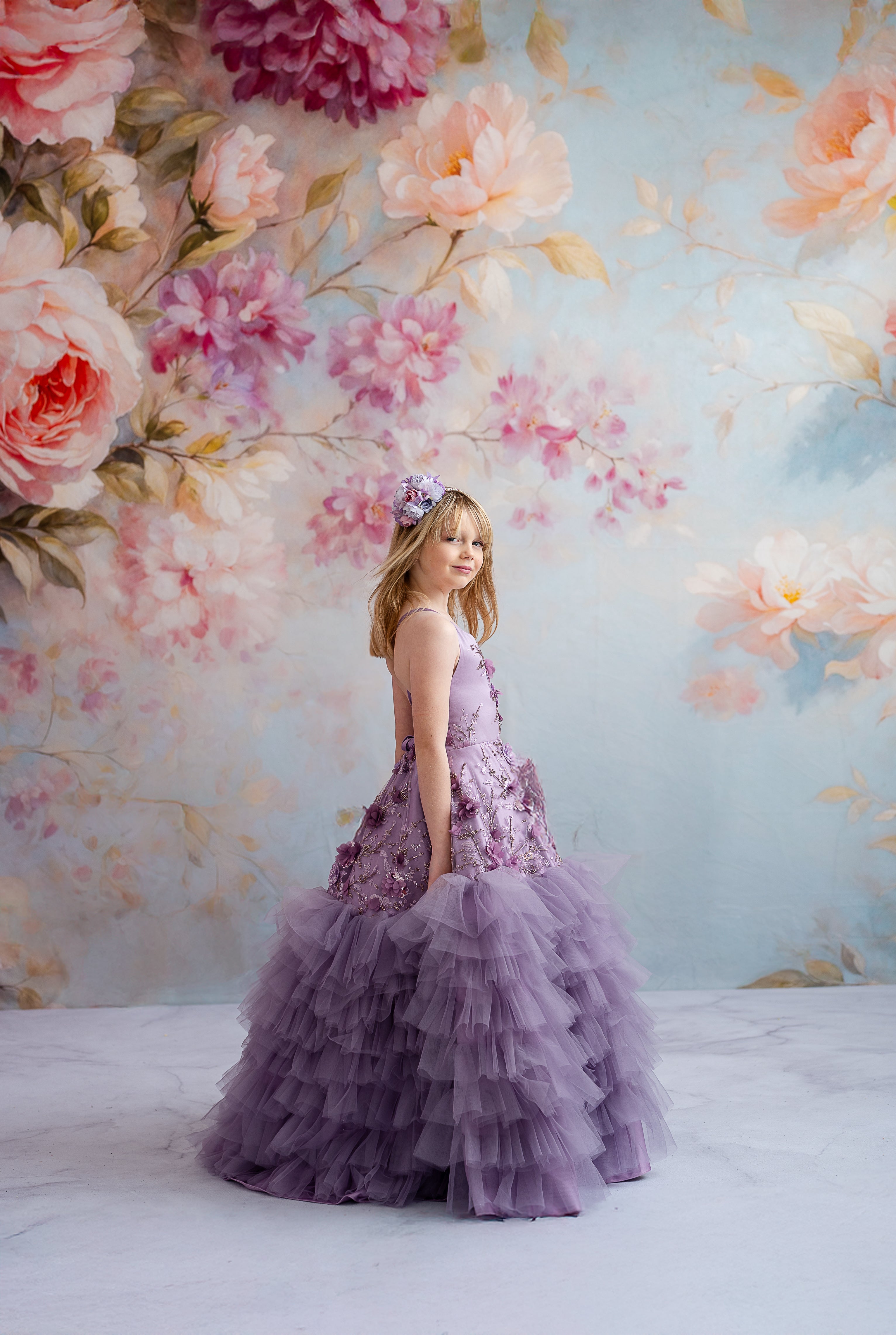 "Lavender floor-length gown adorned with delicate floral appliqués and detachable puff sleeves for a whimsical, versatile look."
