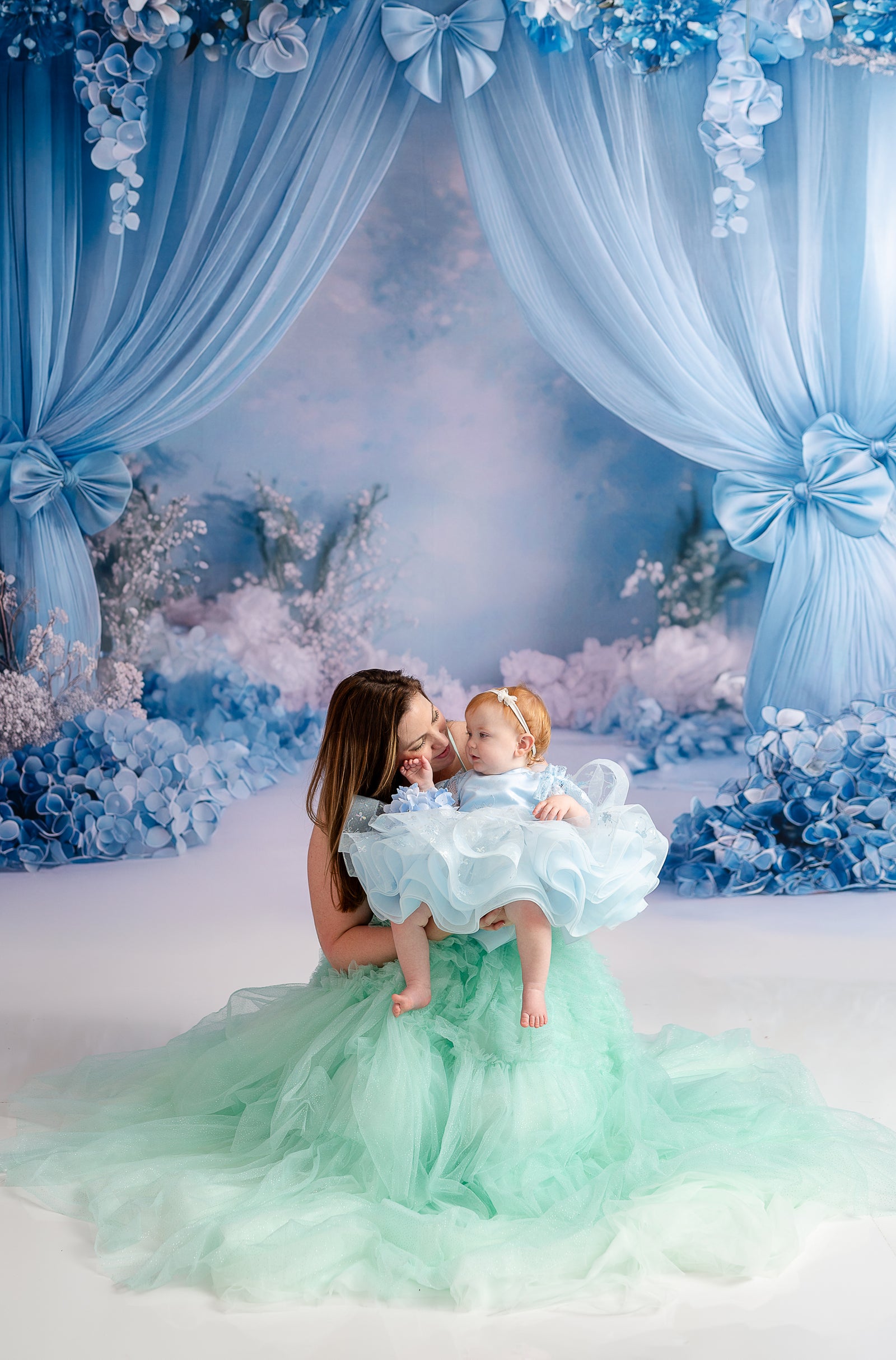 A pair of coordinating gowns create a magical mother-daughter moment in a styled photography session.
