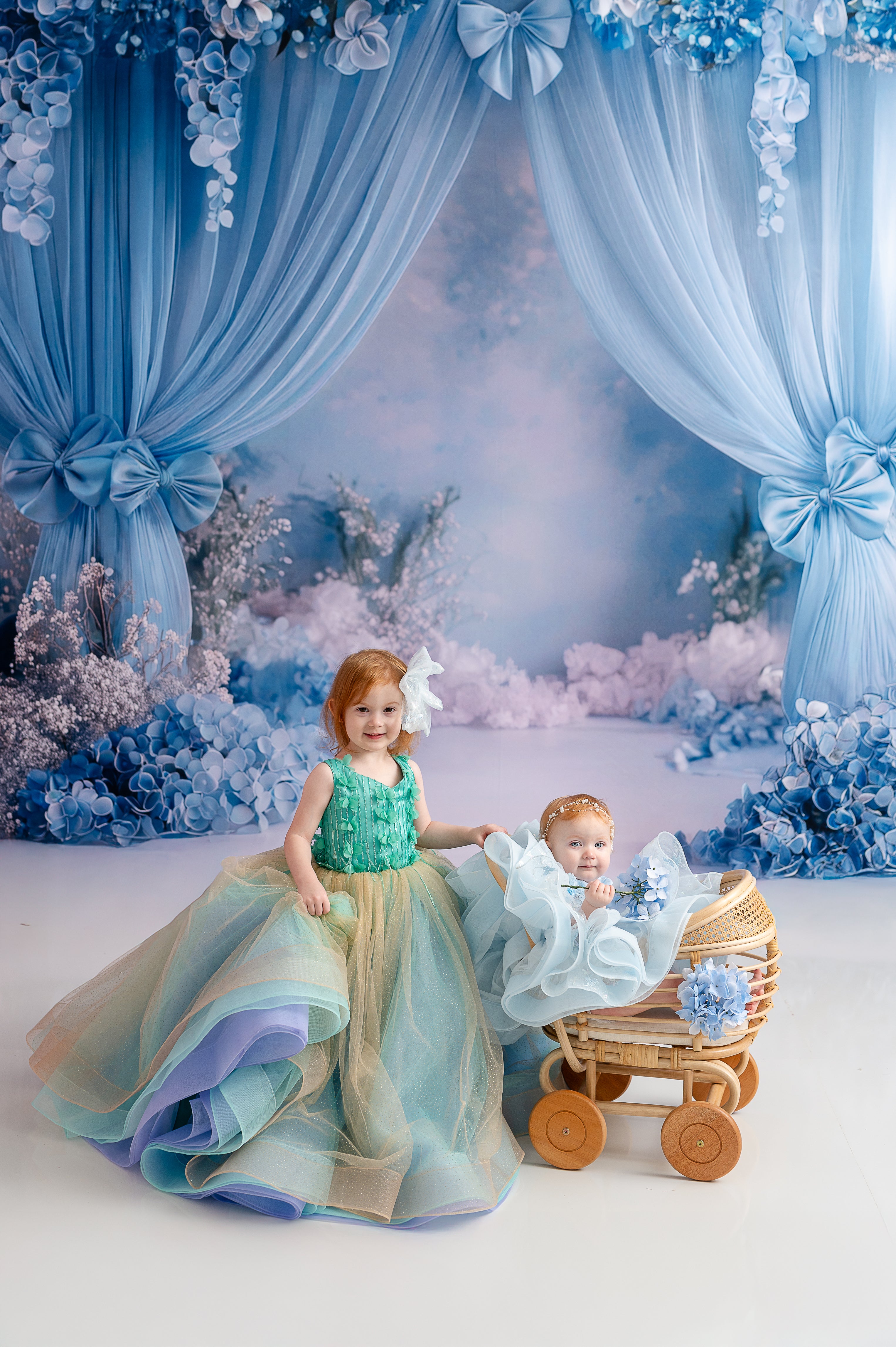 A young girl in an aqua and gold tulle gown twirling gracefully in a whimsical blue floral backdrop.
