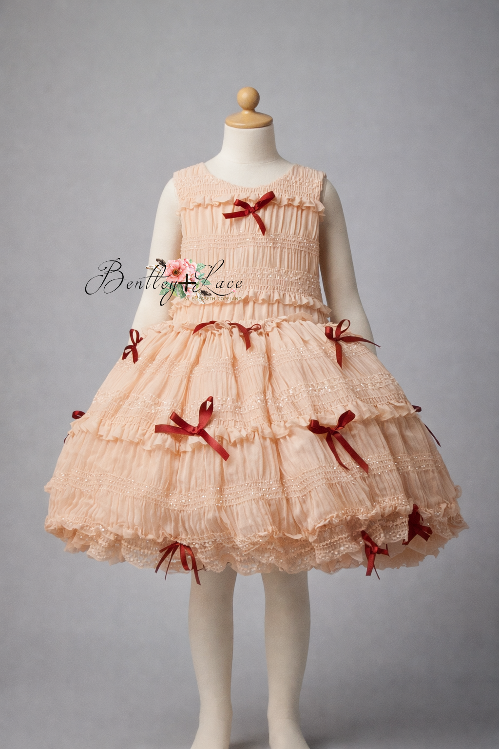 Pink dress with red bows on a mannequin against a gray background