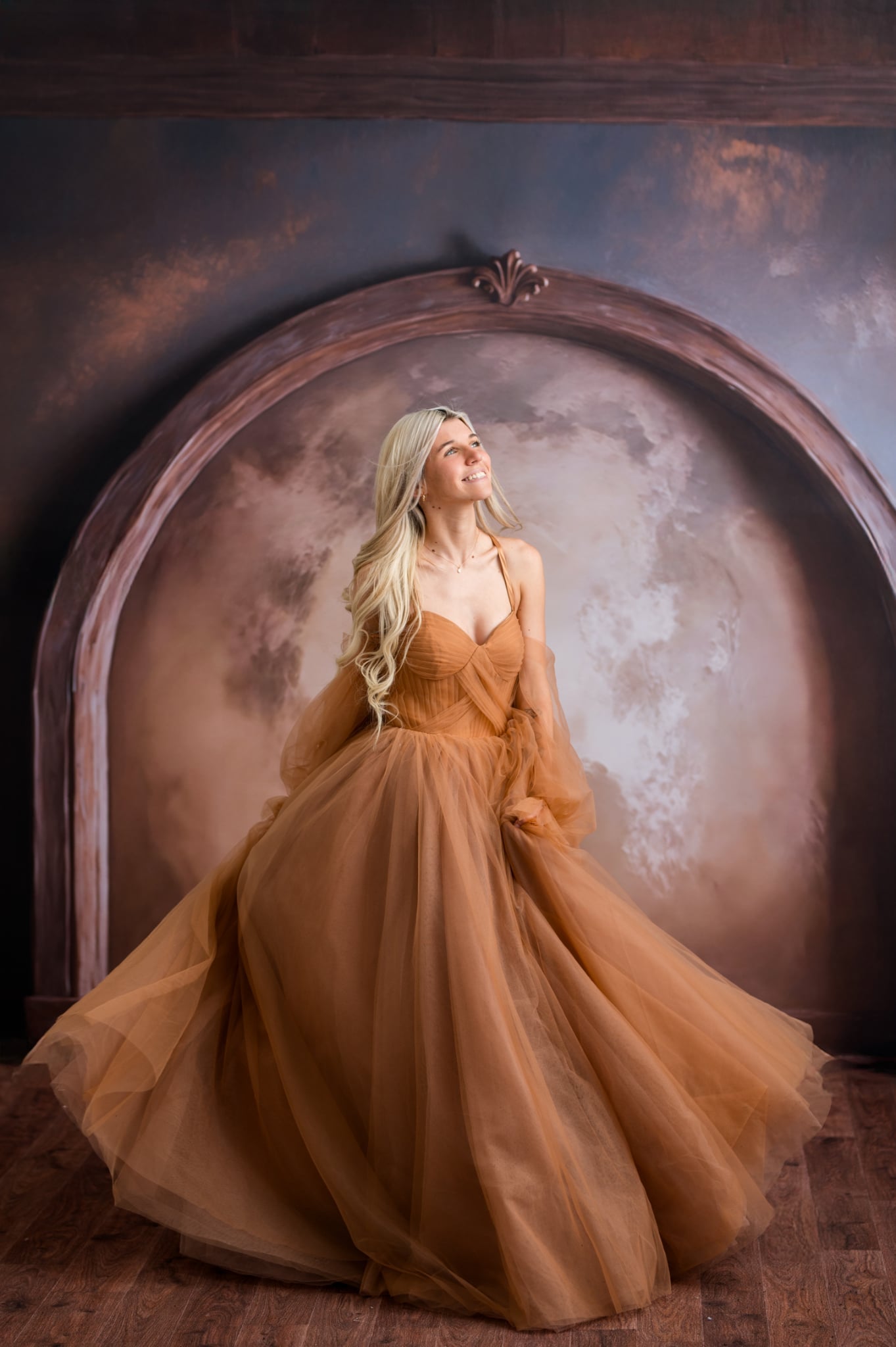 Woman in a long, flowing dress standing in front of an archway with a textured wall.
