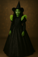 Person in a witch costume with green face makeup against a brown background