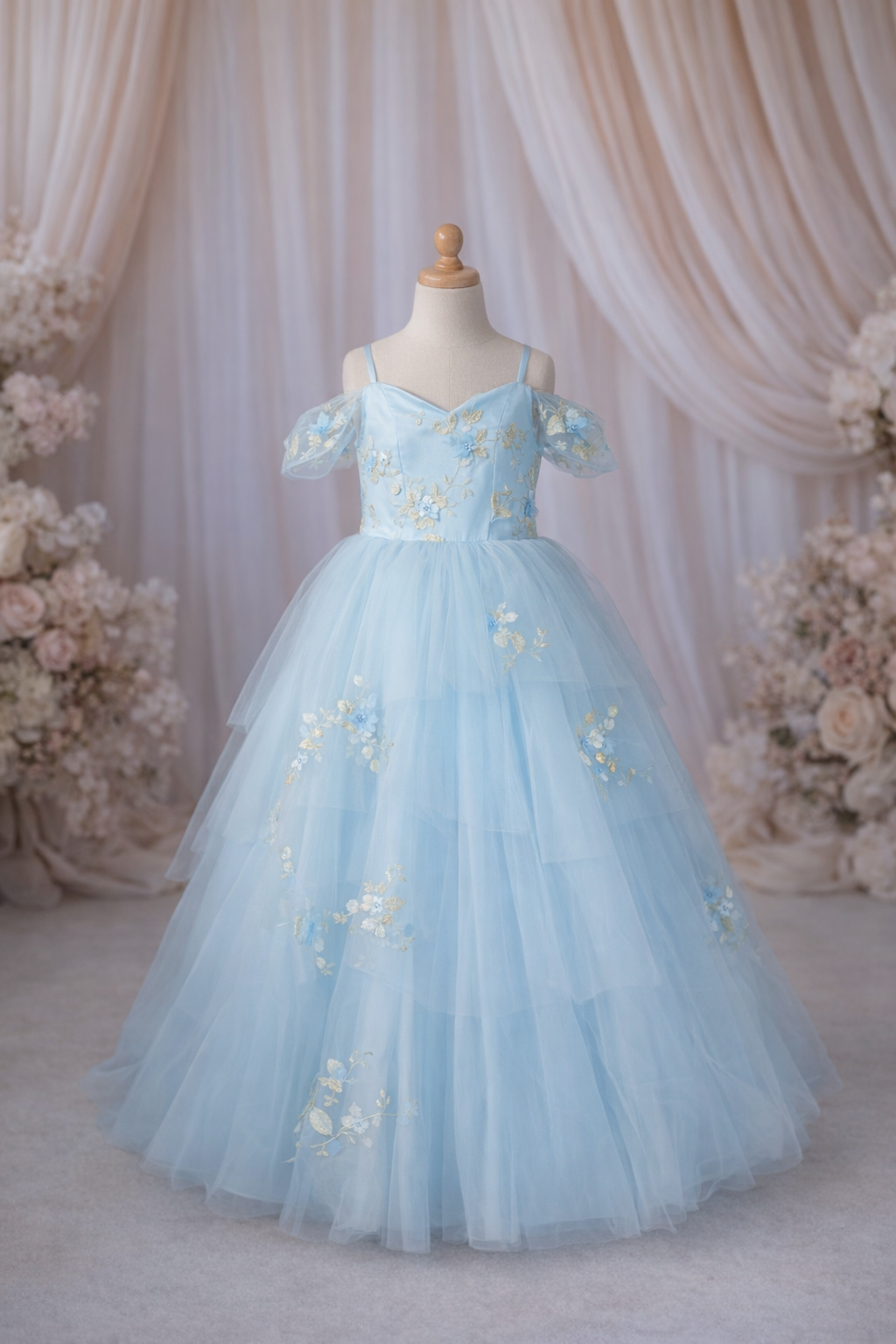 Light blue floral dress on a mannequin against a draped fabric and floral backdrop