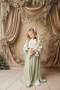 Child wearing Eleanor’s Dream vintage sage green dress with gathered sleeves and classic collar for styled photography sessions.

