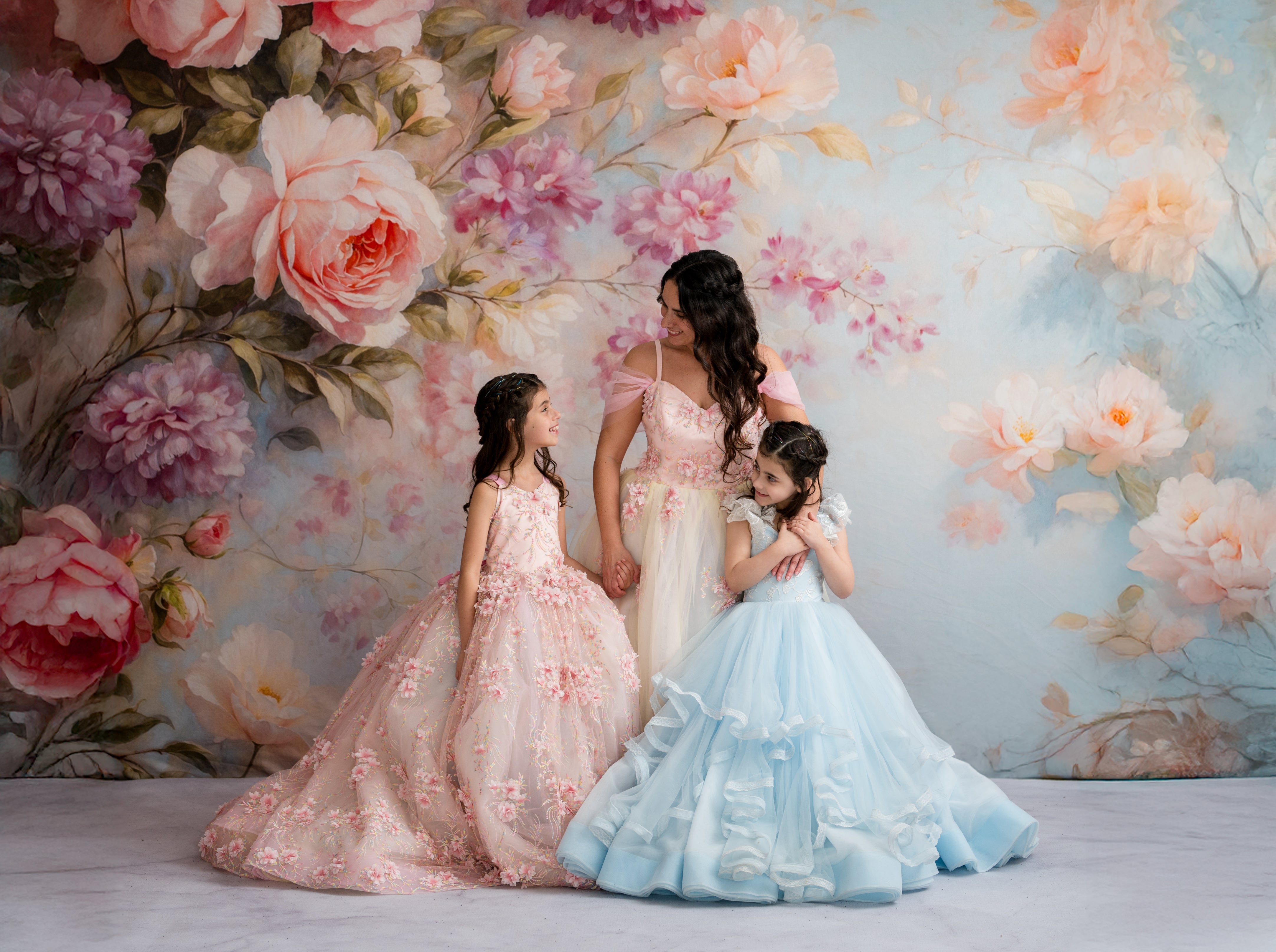 Three women in floral dresses standing against a floral backdrop