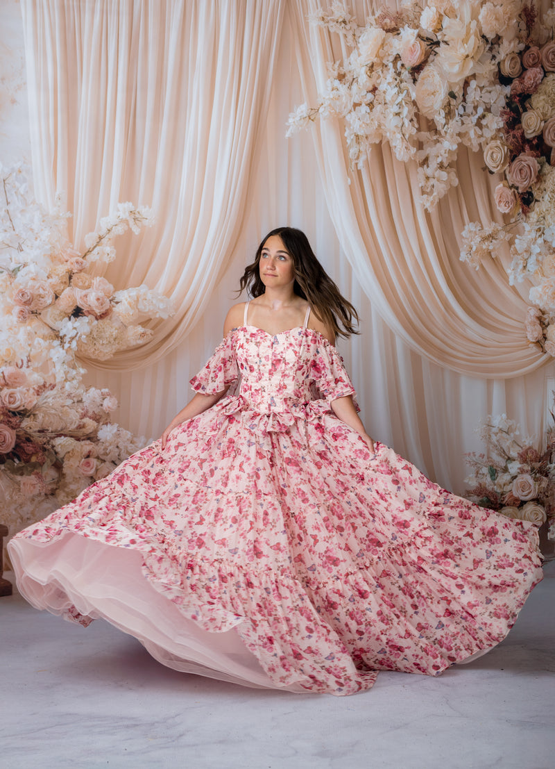 Woman in a pink floral dress standing in front of a floral backdrop