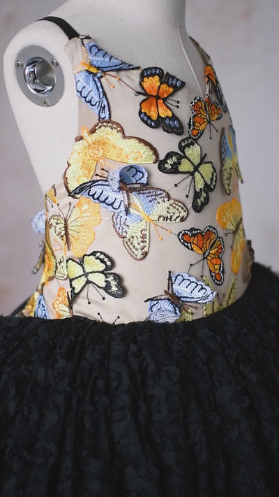 Elegant butterfly-themed gown with a golden bodice and a dramatic black skirt for special occasions.
