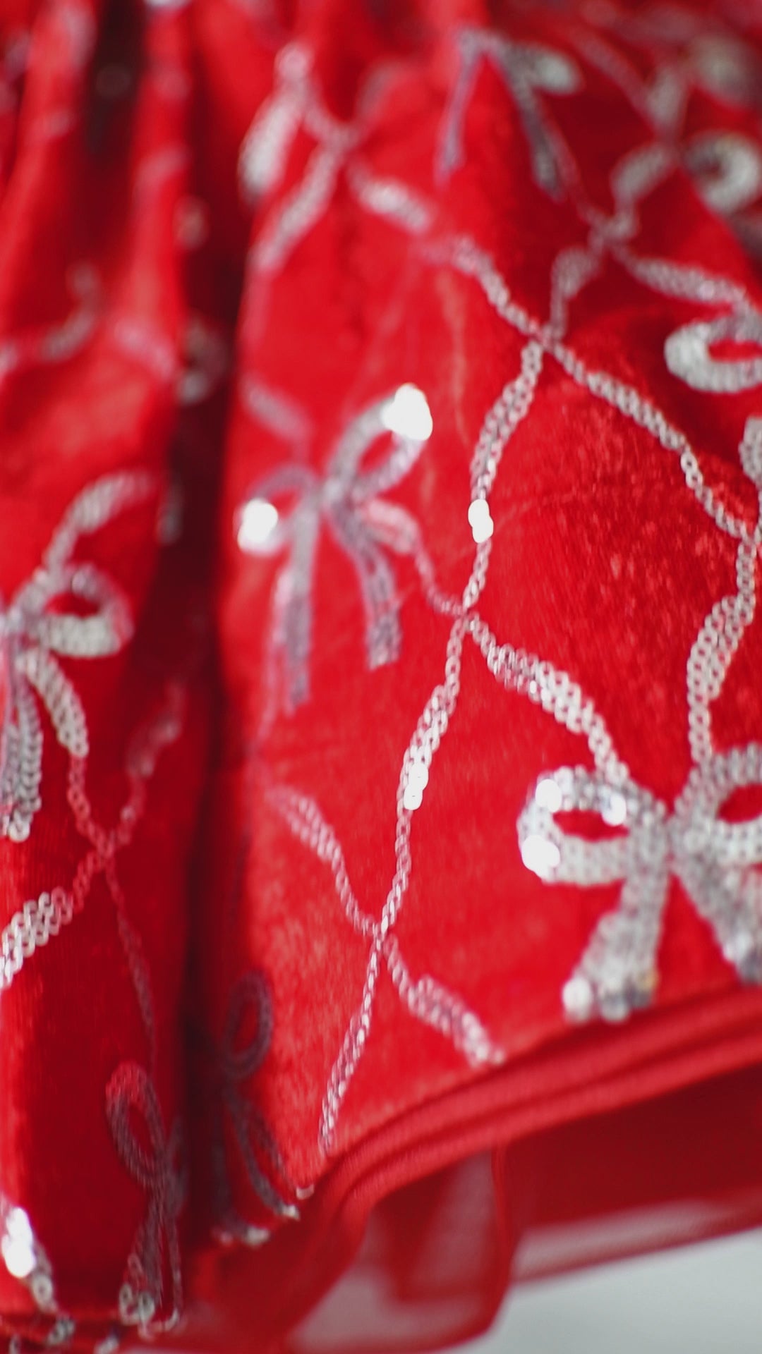 Close-up of red satin bow on the bodice of a festive children's velvet dress.

