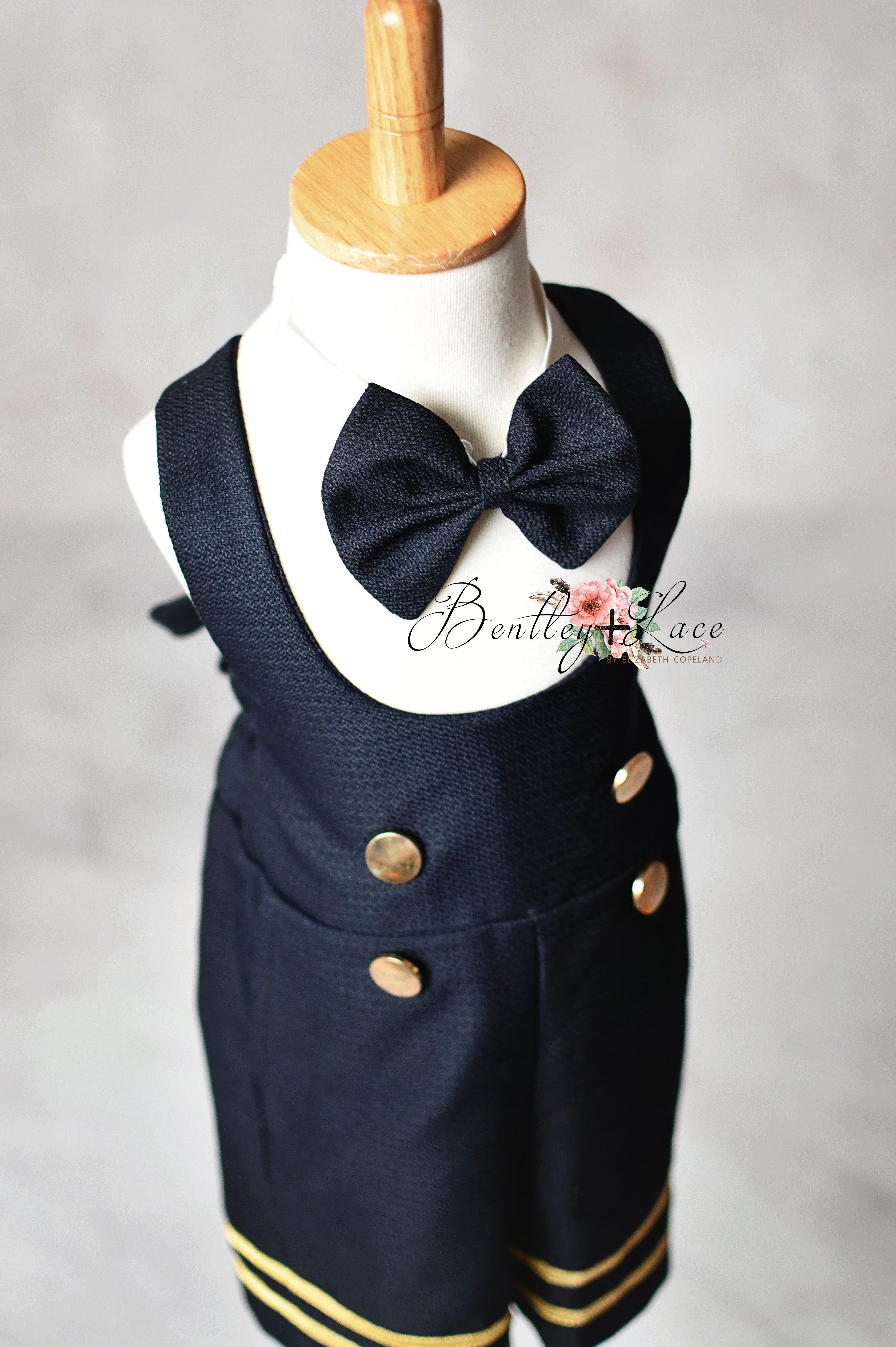 Navy blue children's outfit with bow tie on a mannequin against a plain background