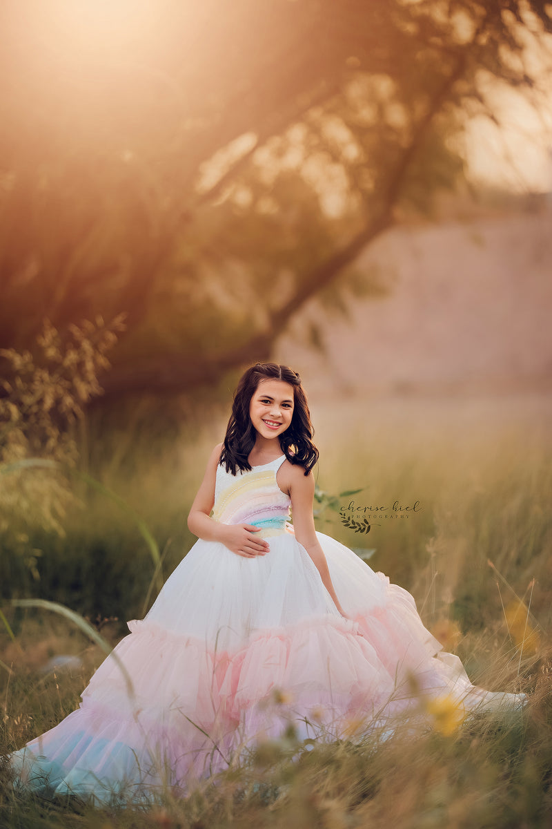 A playful, whimsical dress designed for dress-up, featuring a fitted rainbow pattern with ruffles. 
