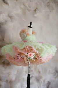 A floral silk fabric dress with a ruffled design and tulle skirt, predominantly in pastel colors, displayed on a mannequin.